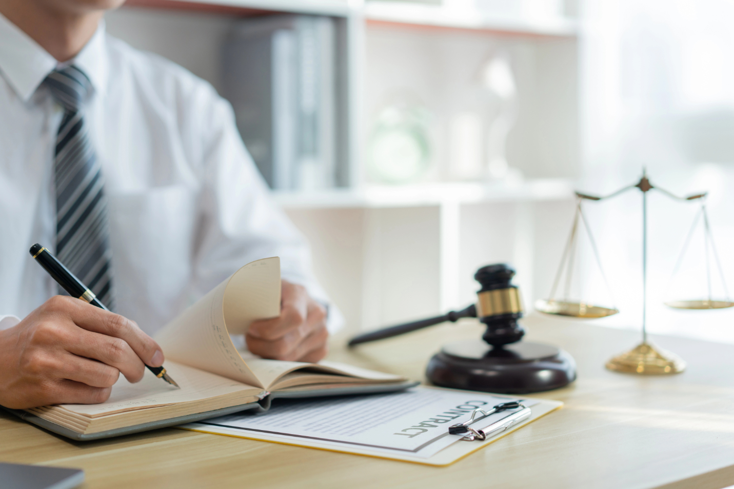 Law consultancy concept A male prosecutor reviewing his sentences of contract on his own notebook before writing them down on the contract paper